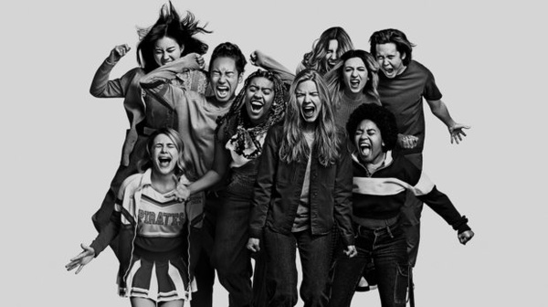 filmes bons para assistir - imagem mostra um grupo de várias adolescentes de diferentes etnias gritando e pulando. A foto está em preto e branco, com as meninas à frente de um fundo branco