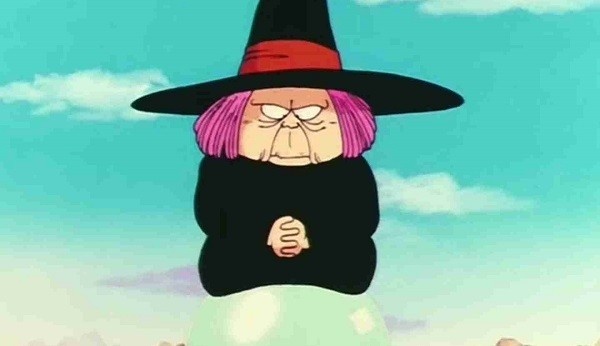 Uma senhora baixinha com cabelo rosa e chapéu de bruxa parece flutuar em cima de uma bola de cristal Trata-se da vovó Uranai